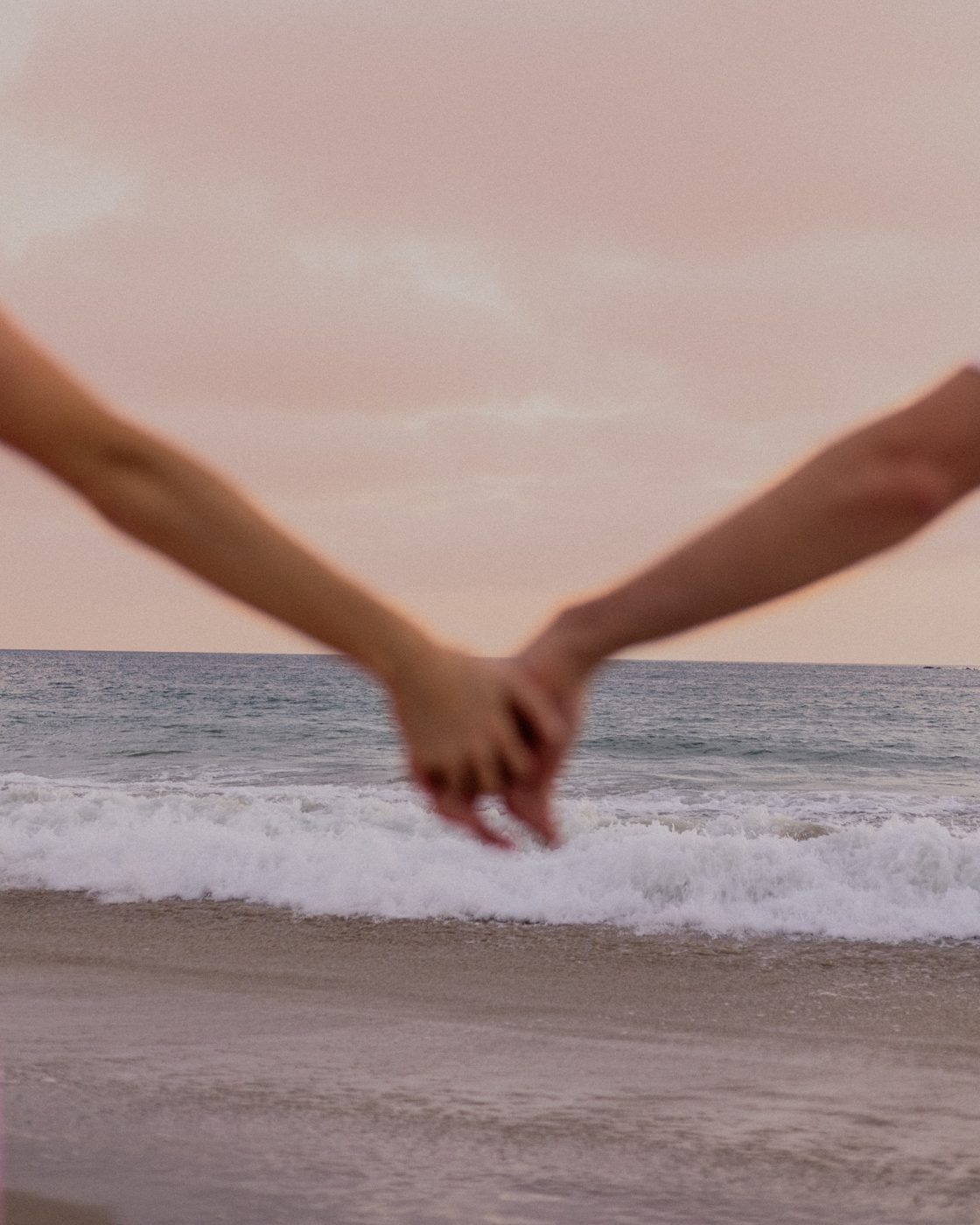 A couple holding hands beside the sea